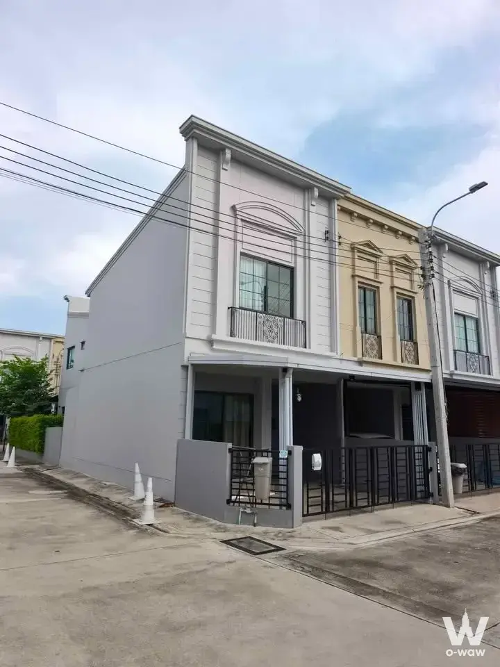 Two-story townhouse exterior for sale in Siri Place Megabangna featuring pale-grey stucco and arched windows
