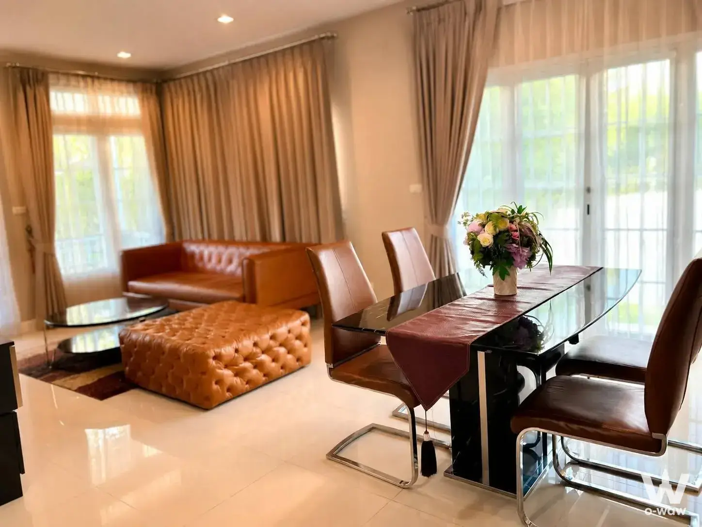 Open-plan living and dining area in a 3-bed Burasiri Panya-Indra condo featuring tan leather seating and floor-to-ceiling