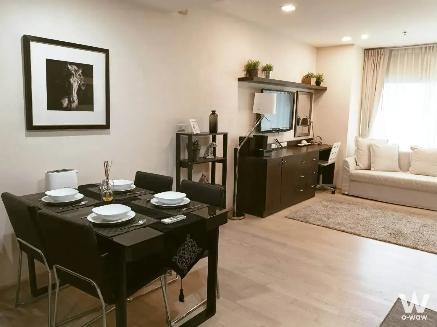 1-bed condo for sale in Noble Remix displaying an open-plan living and dining area with black glass table
