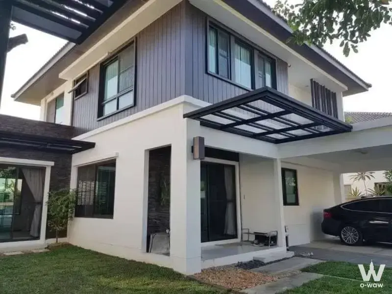 Modern two-story house exterior in Mantana Bangna Km.15 with white and grey facade, black pergola, and carport