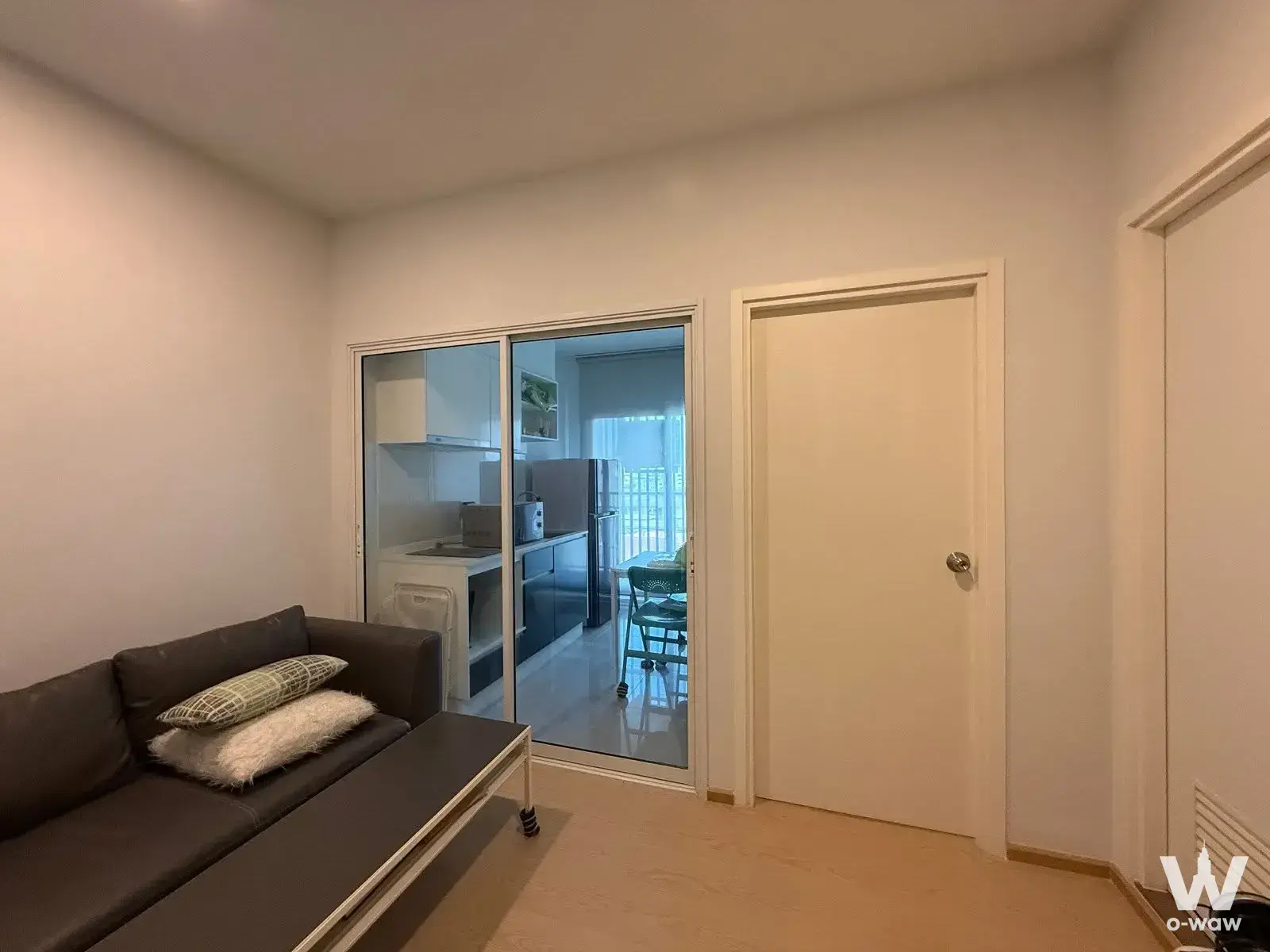 Living room with dark sofa and glass partition in this 1-bed rental at The Tree Sukhumvit 71-Ekamai