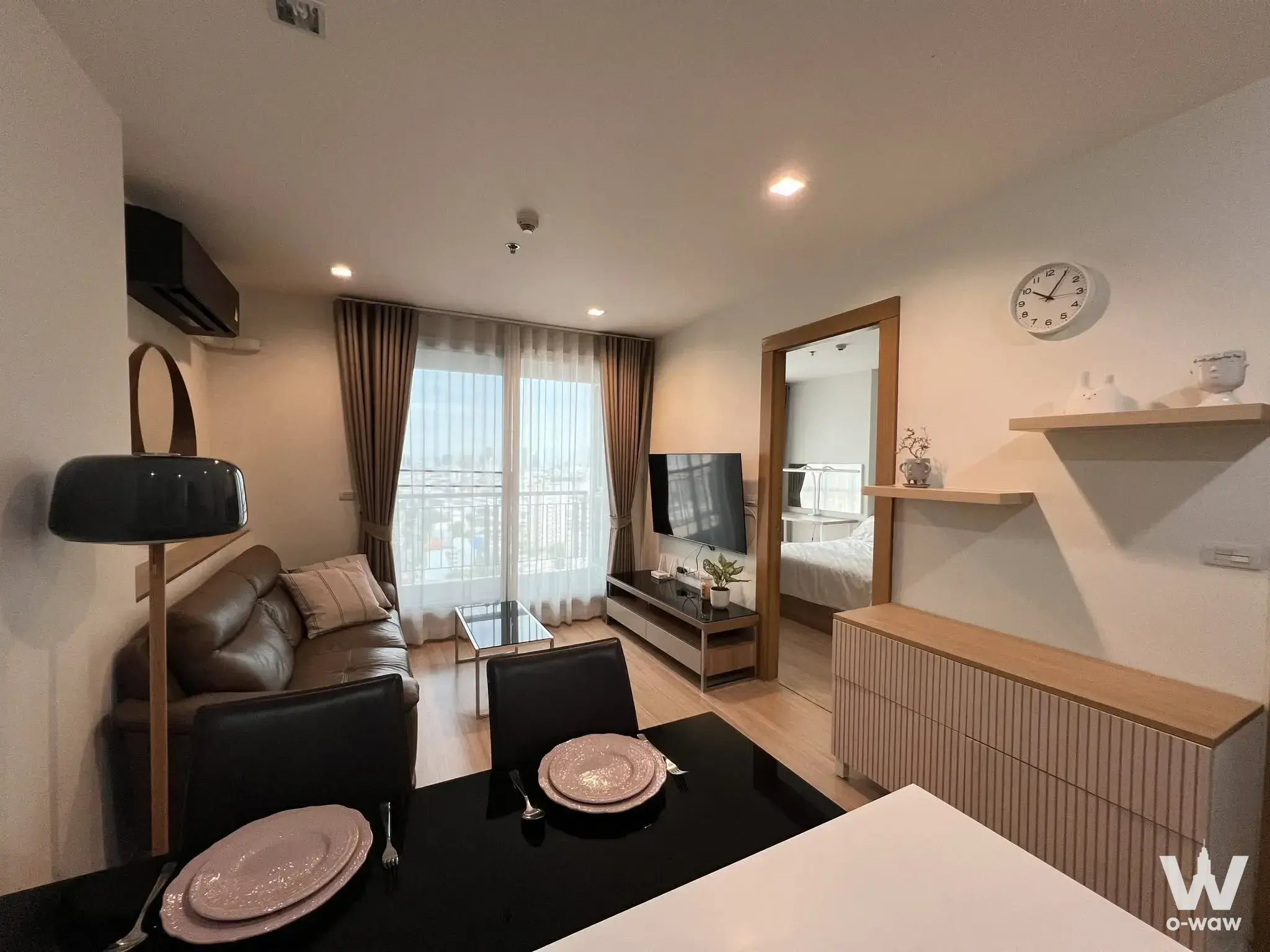 Open-plan living space in a RHYTHM Ratchada-Huaikwang condo with leather seating and city views