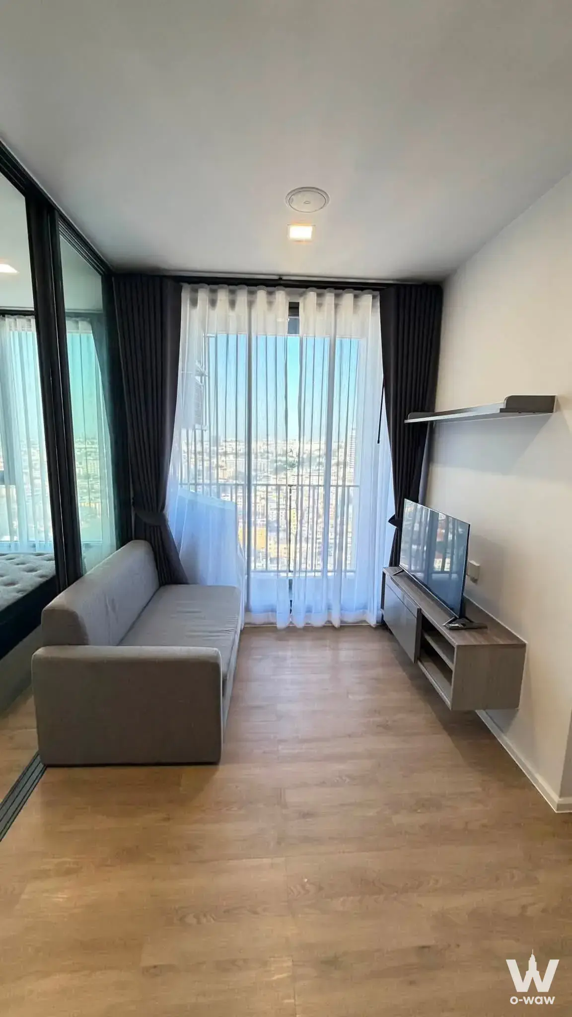 Modern condo living room with sofa, TV, and city skyline view