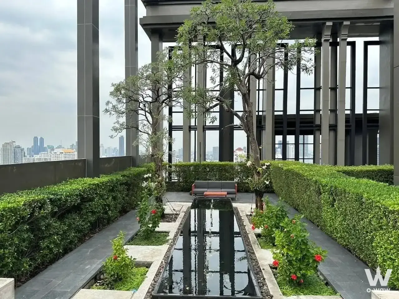 Rooftop terrace at The Crest Sukhumvit 34 condo with reflecting pool, lounge seating, and city skyline views