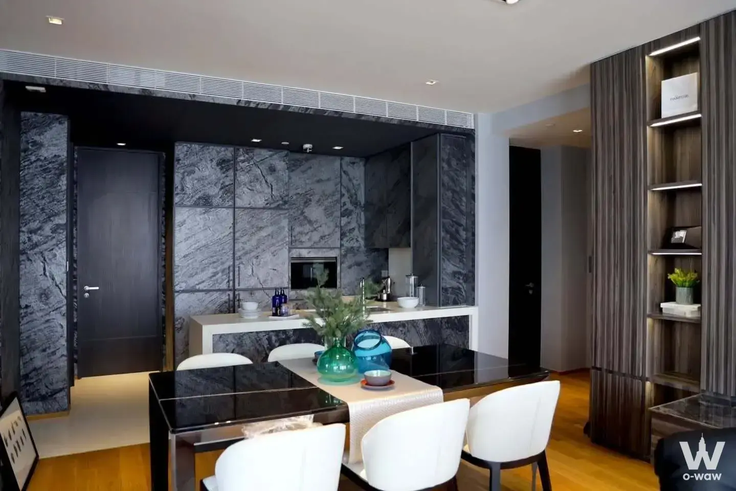 Modern dining area with black table and white chairs in 2-bed condo for rent at BEATNIQ Bangkok featuring grey marble
