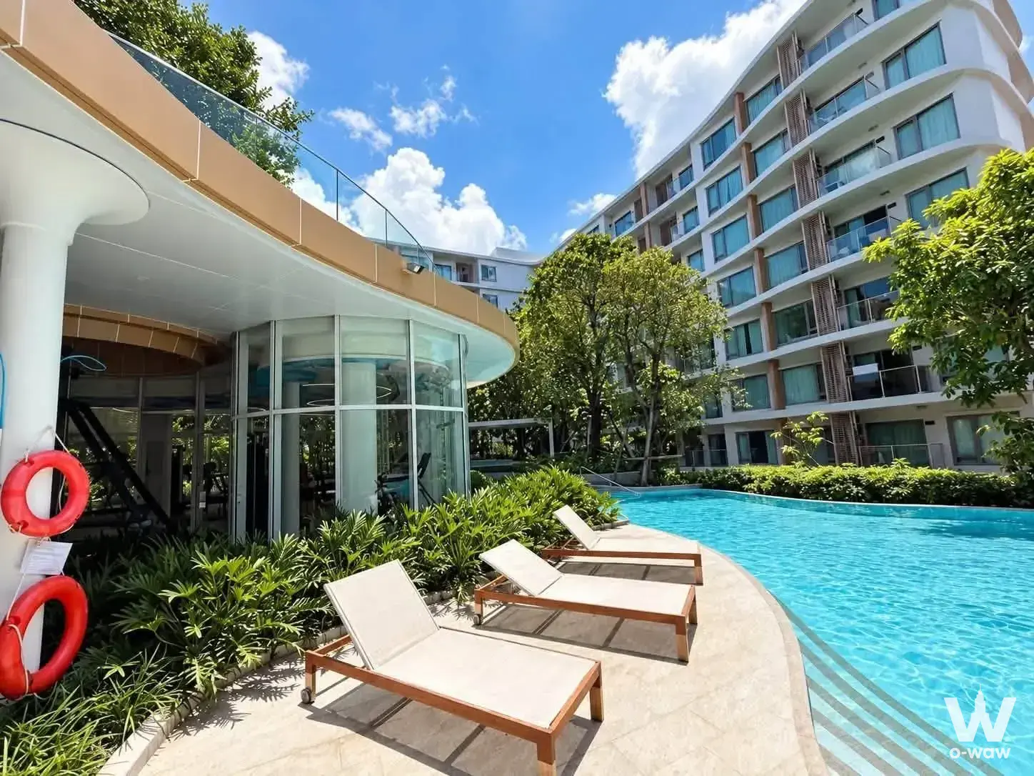 Luxury condo pool deck in Phyll Phuket with curved turquoise water and wooden loungers