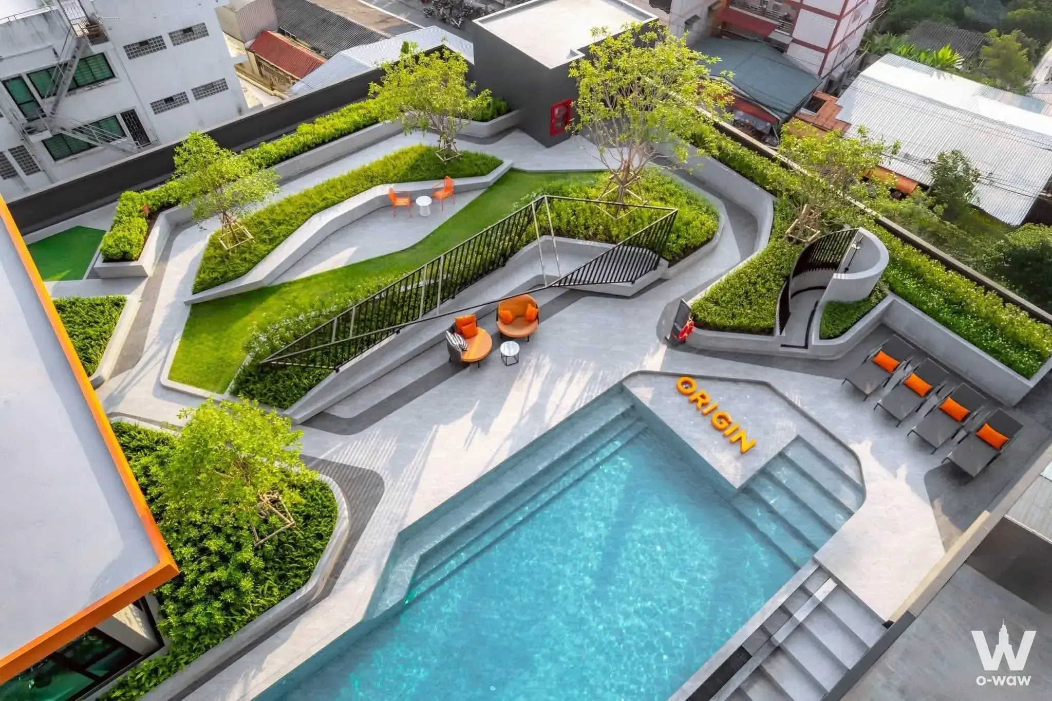 Rooftop pool deck at The Origin condo in Prasaksa featuring orange accents, sunbeds, and urban views