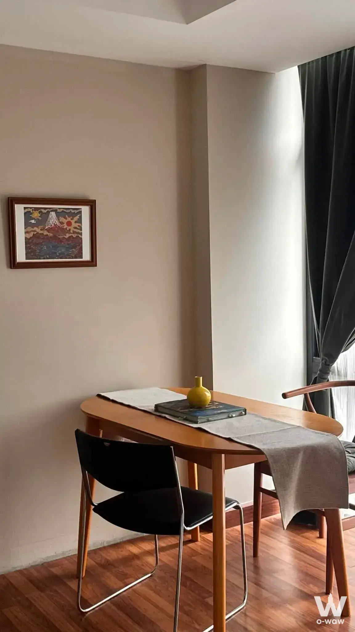Dining nook in this G HAUS condo features an oval oak table and black leather sling chair