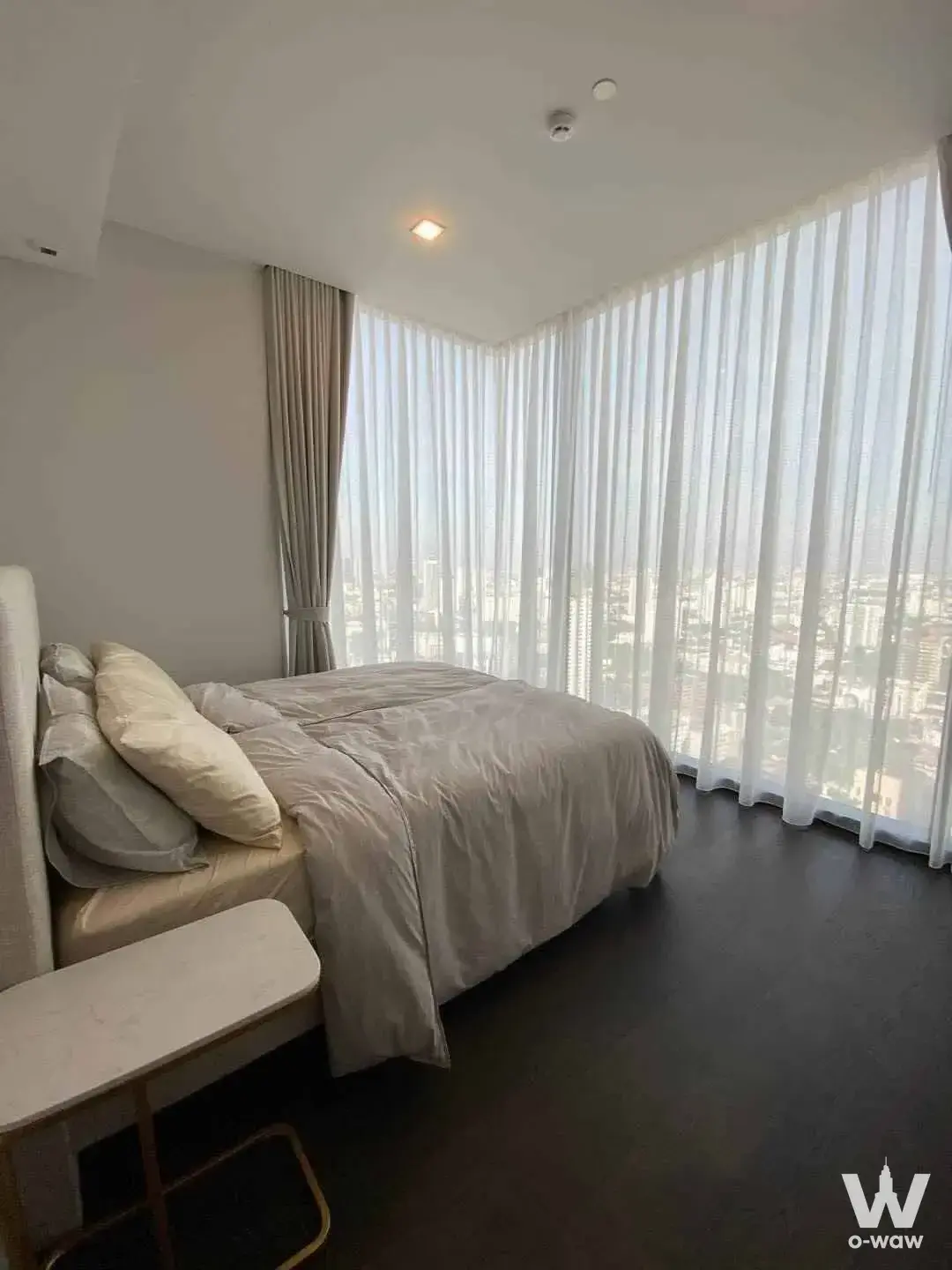 Queen bed and corner windows overlooking the city skyline in a 2-bed LAVIQ Sukhumvit 57 condo
