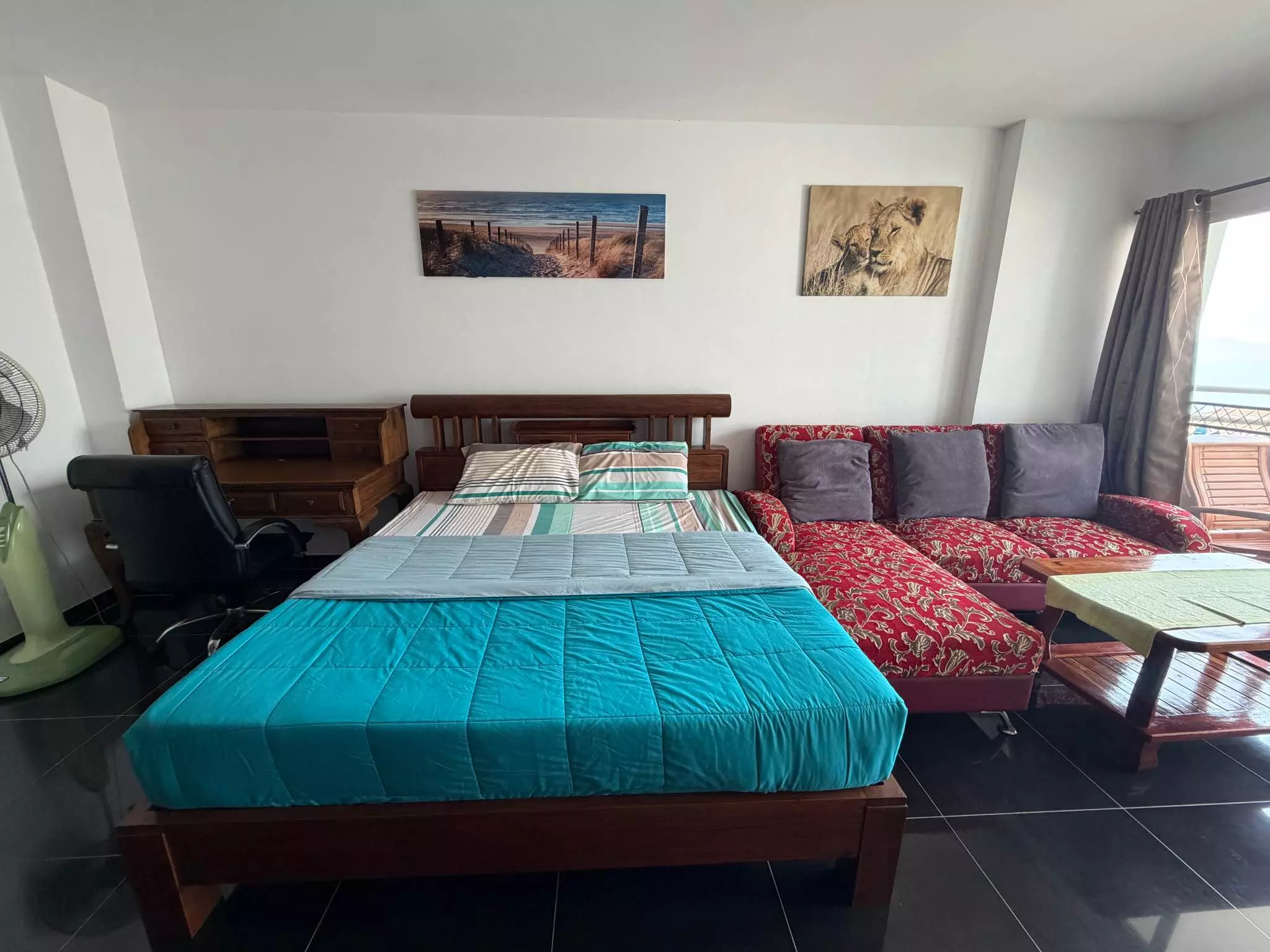 Furnished 1-bed condo bedroom in View Talay 8 with turquoise bedding, red sofa, and balcony access