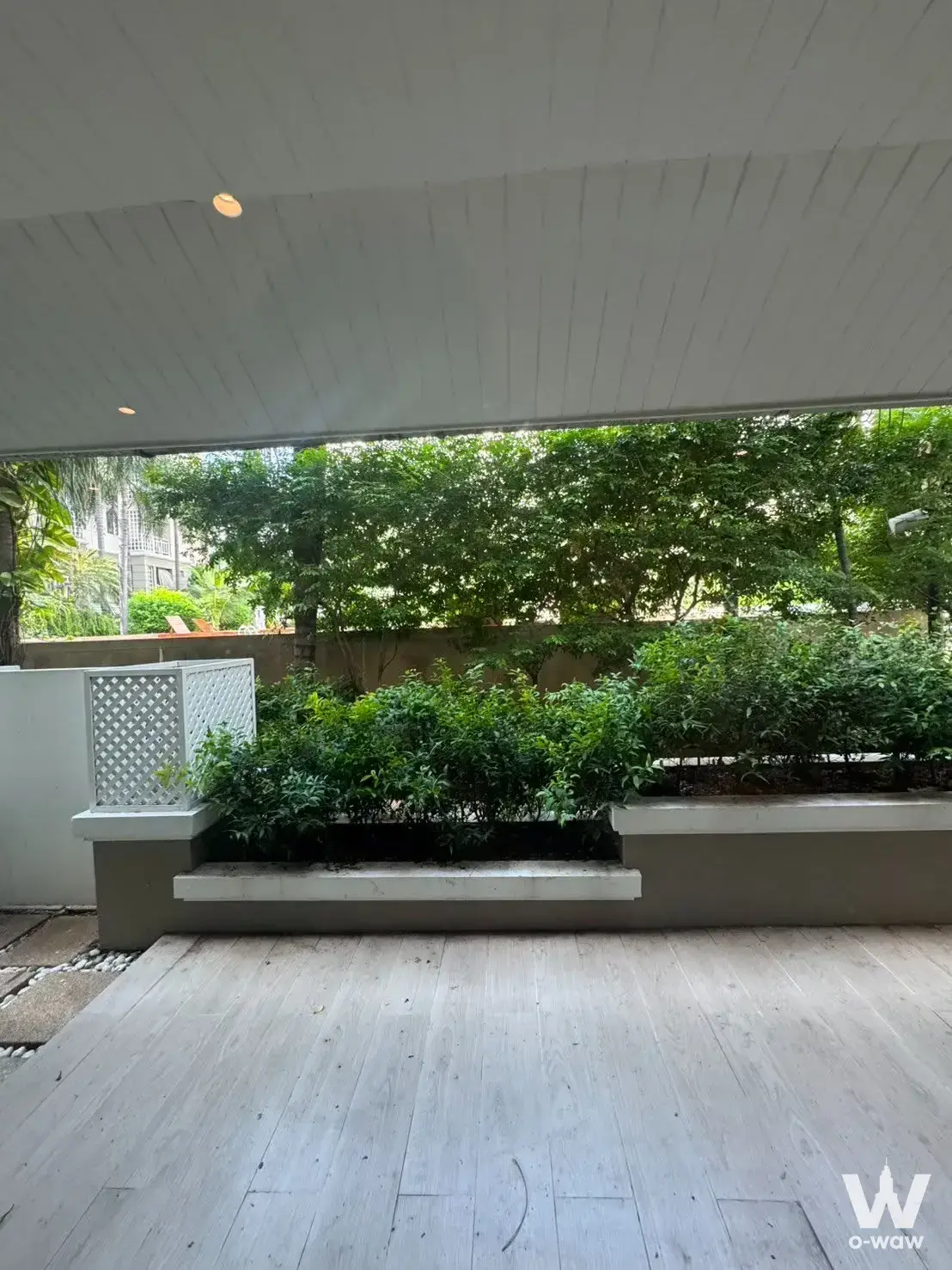 Covered terrace at 3-bed condo for rent in The Bangkok Narathiwat with wood-effect flooring and lush greenery