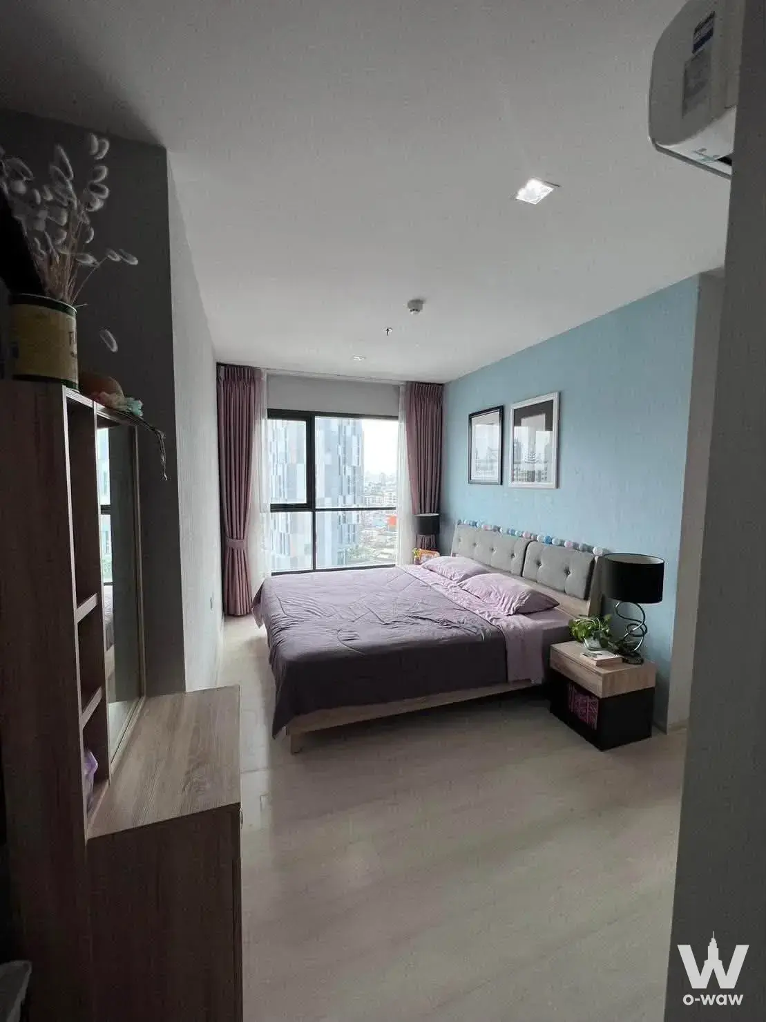 Purple-accented bedroom in Life Sukhumvit 48 featuring light blue walls and city skyline views