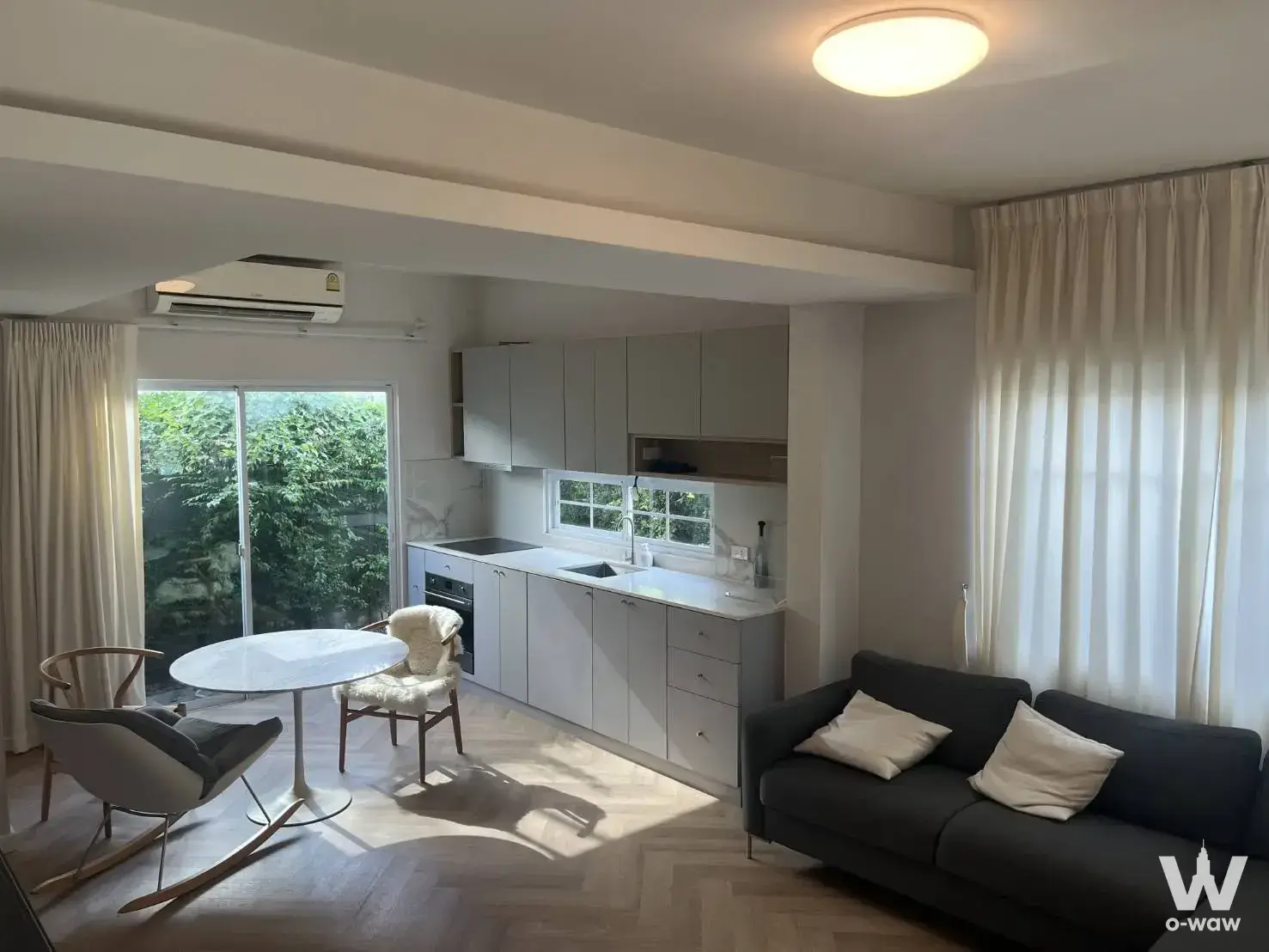 Open living and kitchen in a 2-bed townhouse in Indy 3 Bangna km.7, with herringbone floors and a marble dining table