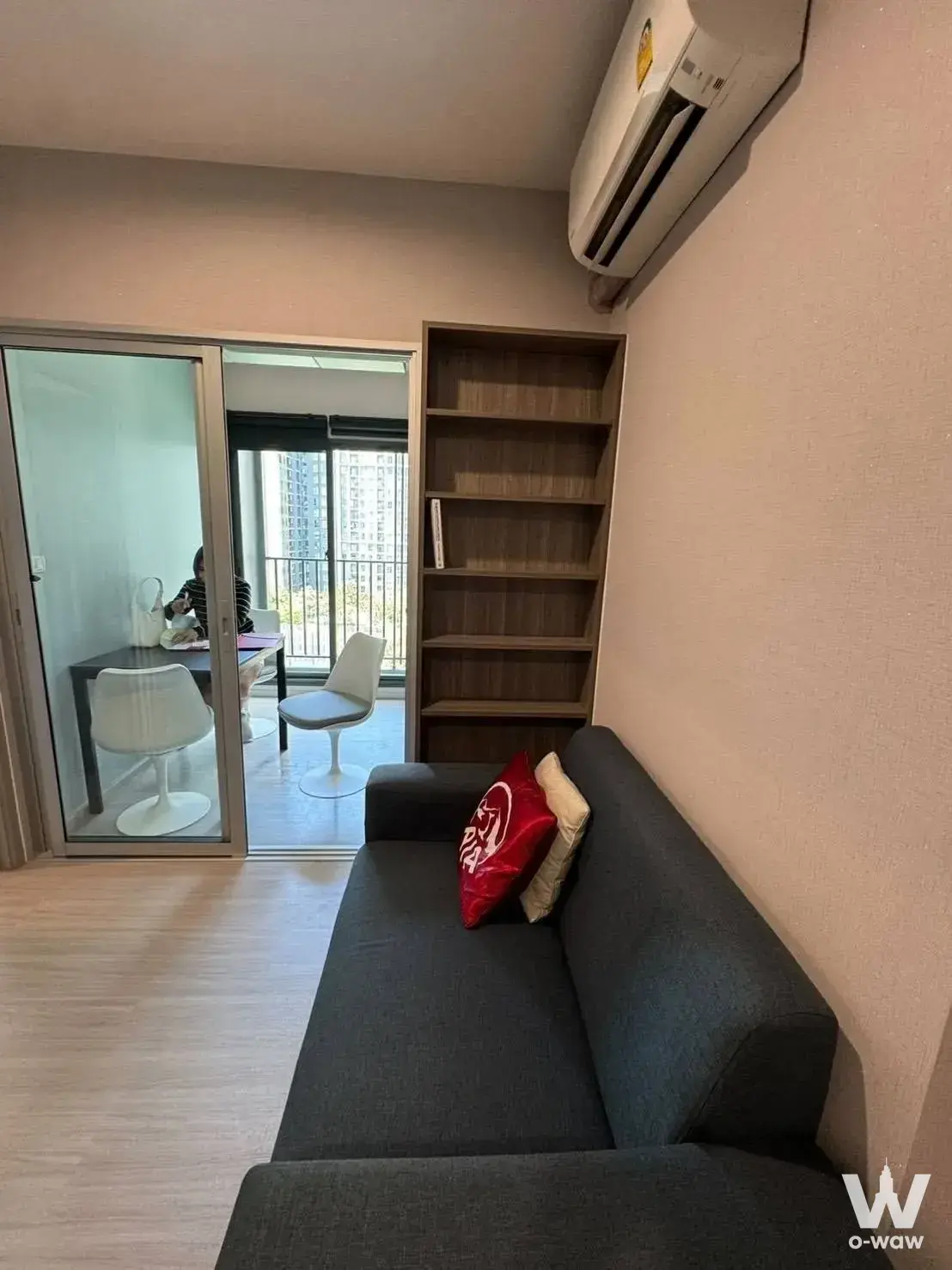 Bright living room with grey sofa and glass doors leading to balcony dining area in 1-bed condo for rent at The Parkland