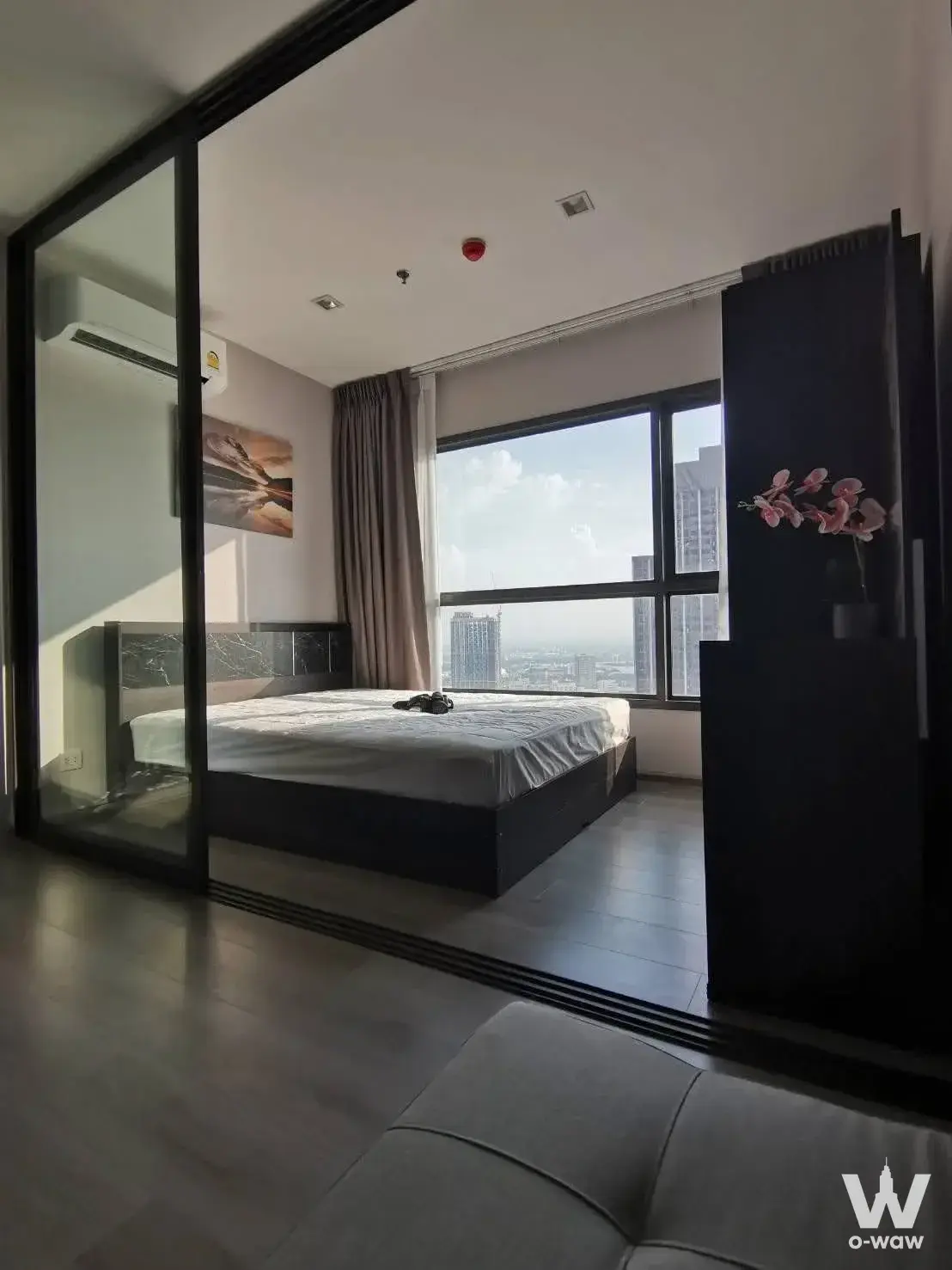 Queen bed in 1-bed condo for rent at The Politan Aqua with city skyline view and modern black accents