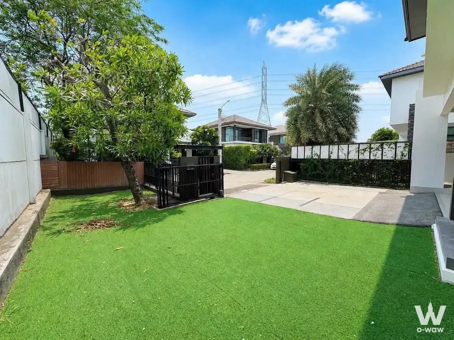 Front yard of 3-bed house for rent in Mantana Onnut-Wongwaen 3 with green turf and open gate