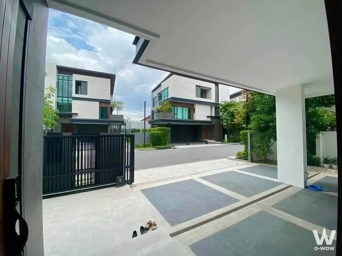 The covered carport entrance of a 5-bed house for sale in The Honor Yothinpatana has a stone driveway and sliding gate