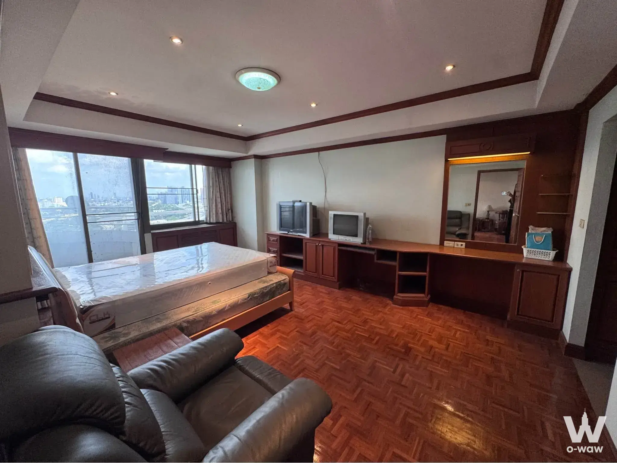 Royal Nine Residence 1-bed condo master bedroom has parquet floors, built-in cabinetry and a city view