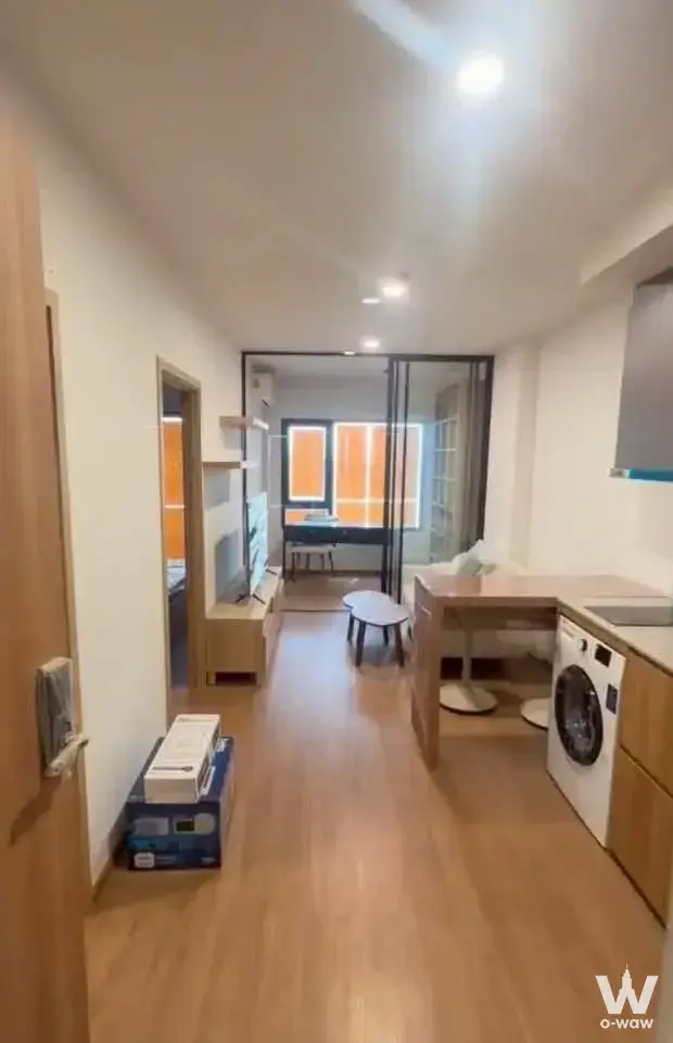 Modern 1-bed condo for sale in The LIVIN Phetkasem with light wood floors, open kitchenette, and glass doors to balcony
