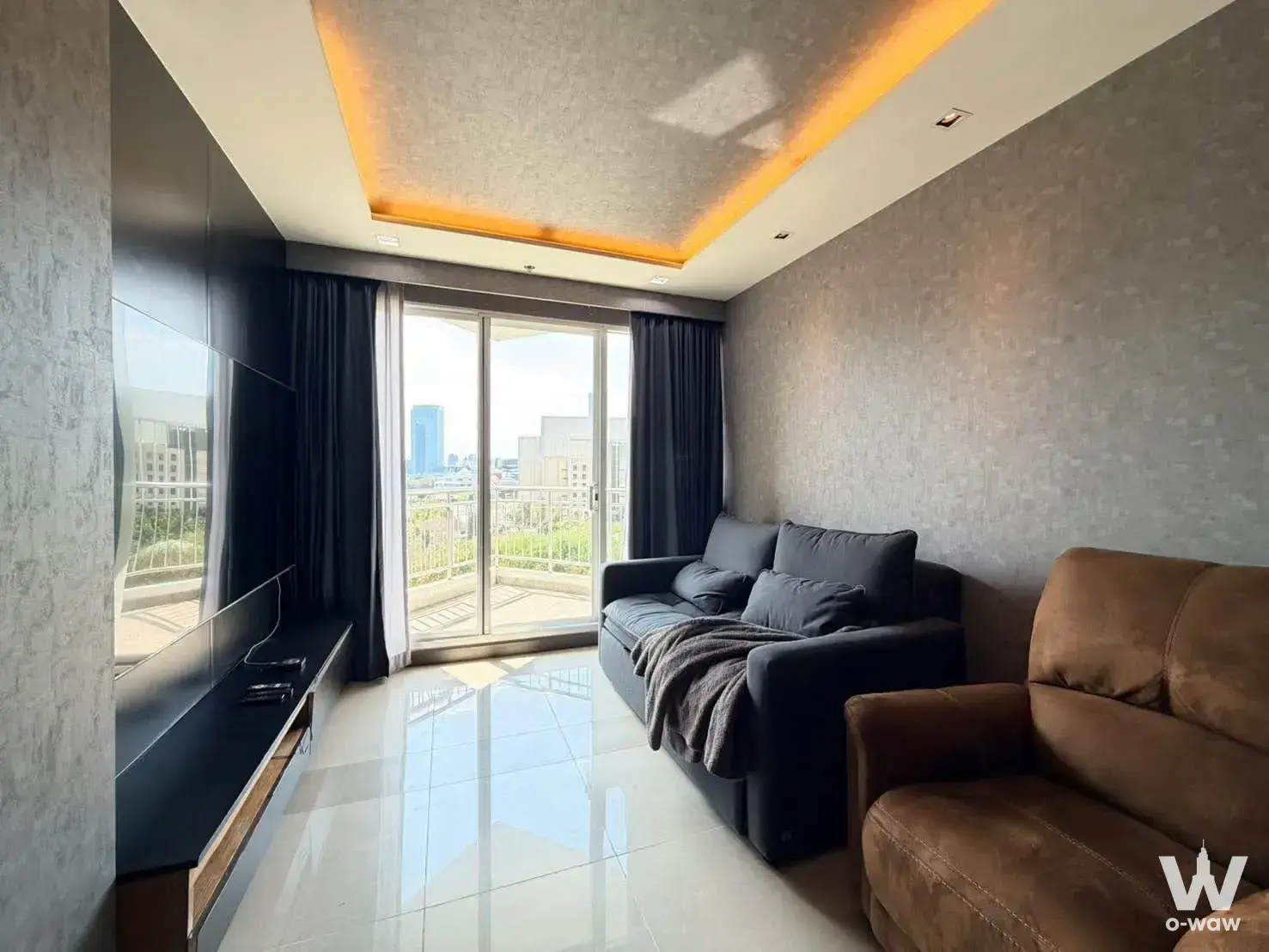 Modern living room in Supalai Wellington II condo for sale featuring glossy floors, grey sofa, and balcony city views