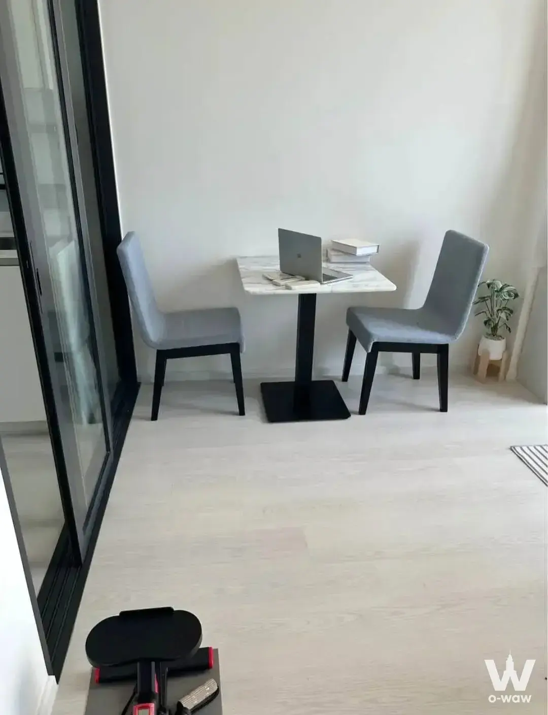 Minimalist dining area in Mazarine Ratchayothin condo with marble table, laptop workspace, and floor-to-ceiling glass doors