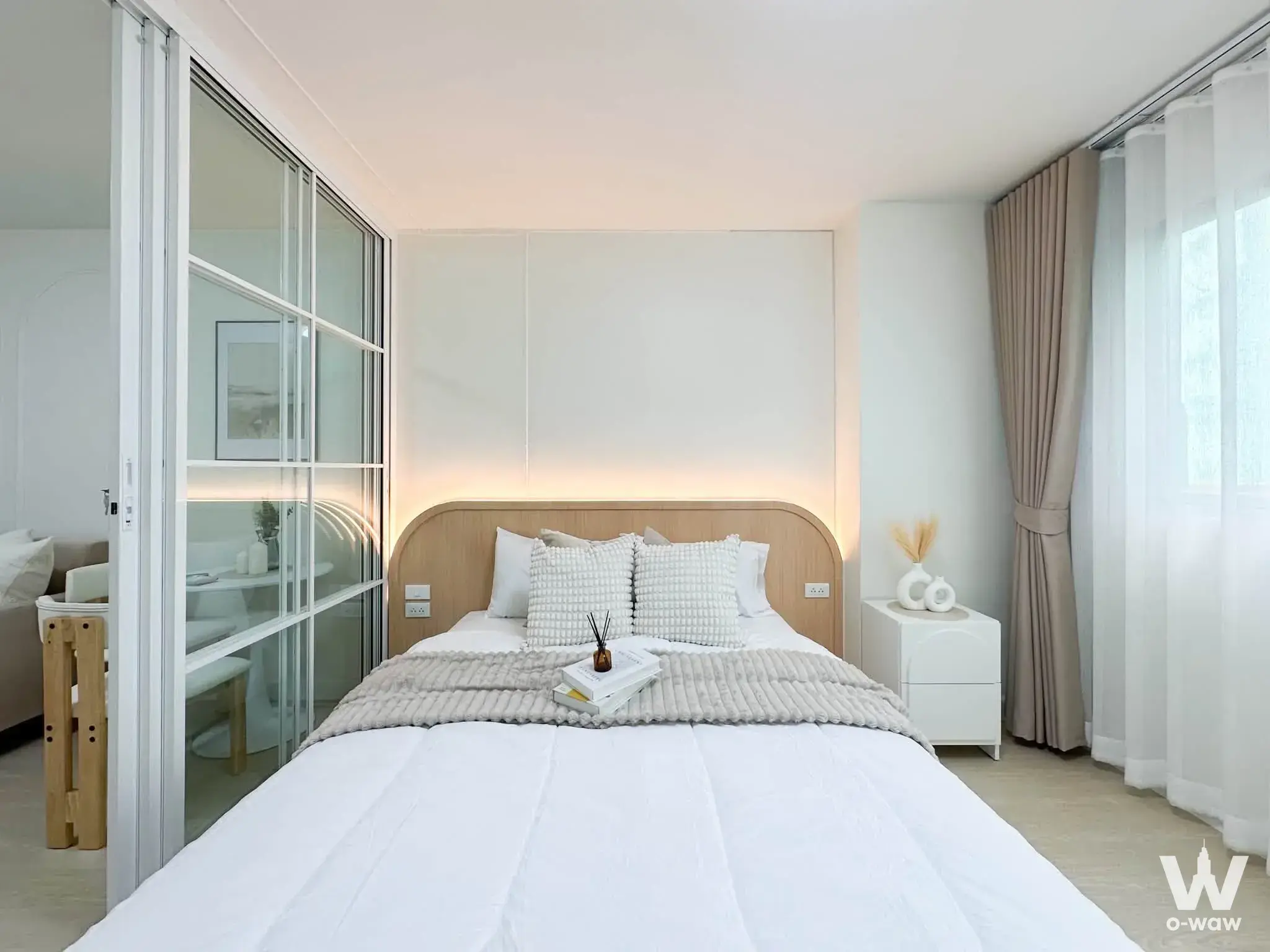 The bedroom in a 1-bed condo for sale in Lumpini Center Lat Phrao 111 has a queen bed and warm LED headboard lighting