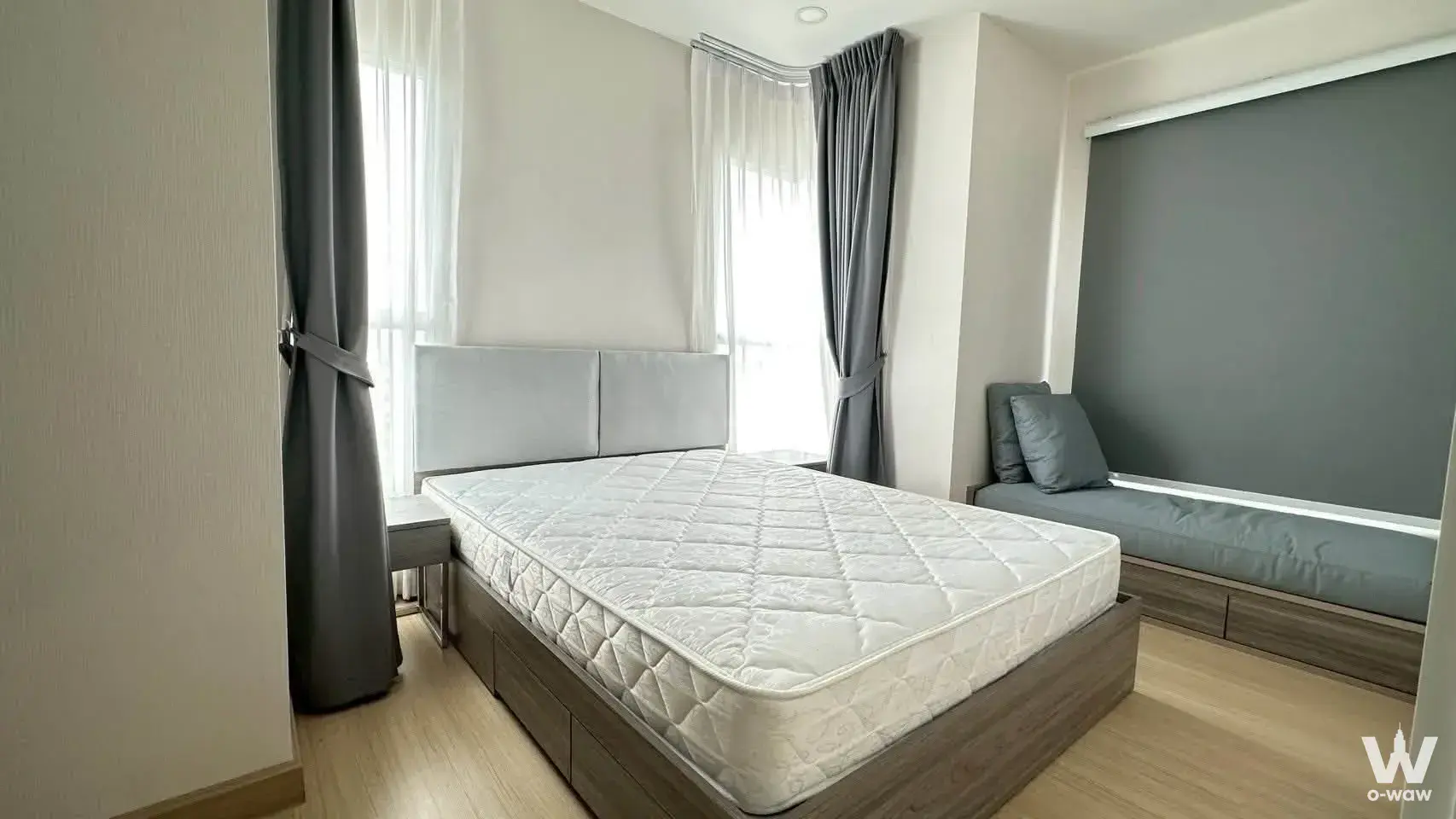 Queen bed with wood frame and built-in window seat in this 2-bed condo for rent at Supalai Veranda Ramkhamhaeng