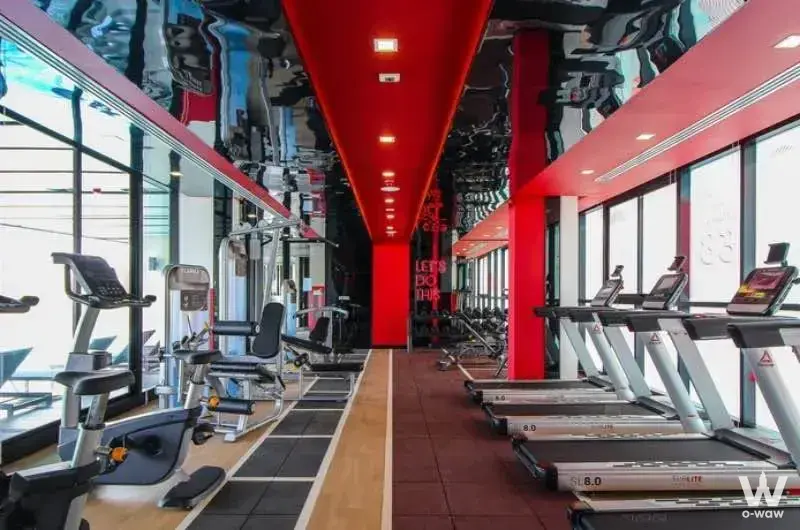 The Station Condo gym offers treadmills, ellipticals, and weight machines under bright lights with red accent columns