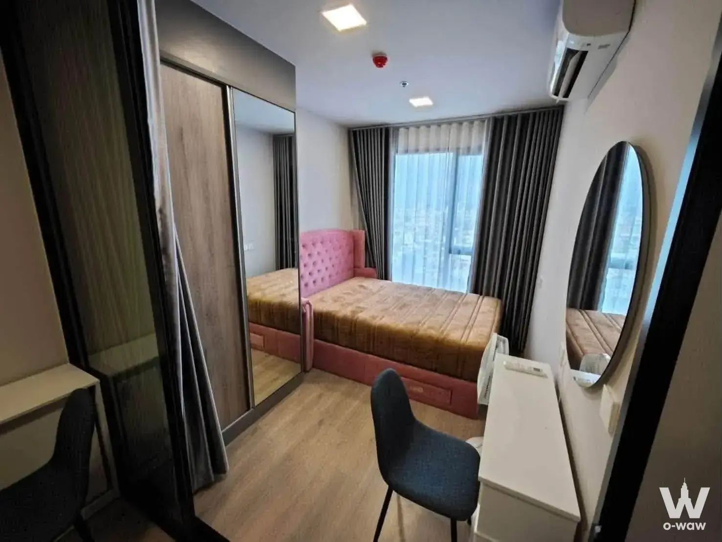 Queen bed with pink tufted headboard and city view in this 1-bed condo for rent at The Privacy Taopoon Interchange