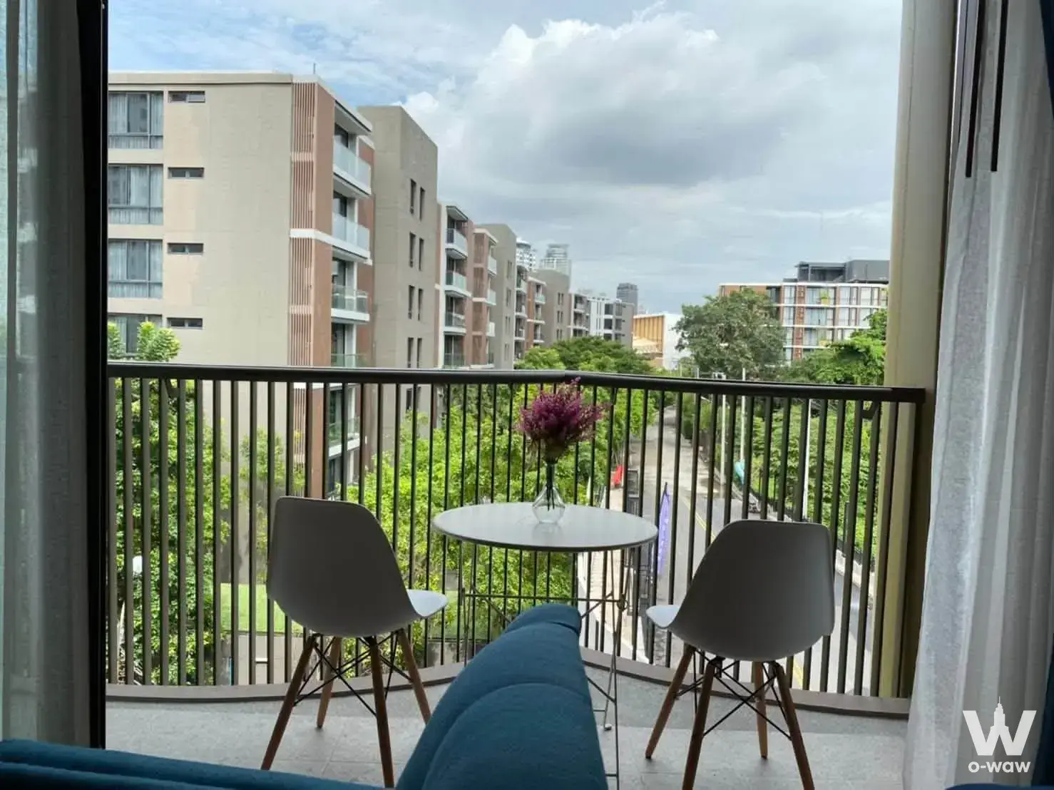 Curved balcony with Eames-style chairs and table overlooking greenery at Kawa Haus