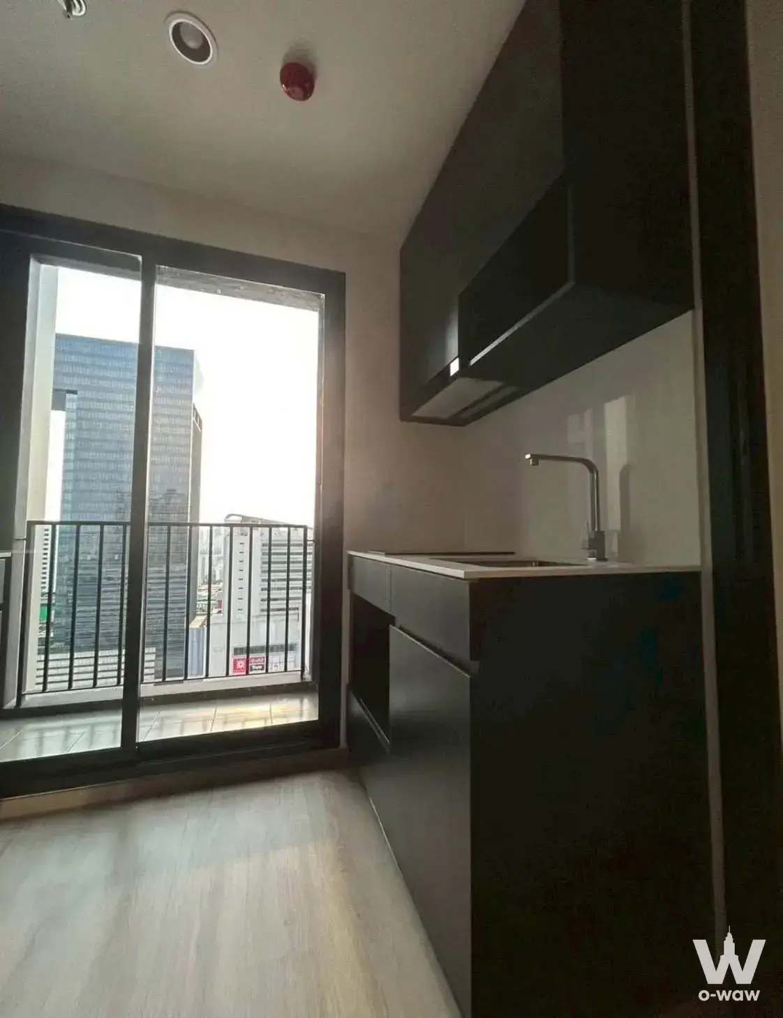 Modern kitchenette with matte black cabinets and city view in 1-bed condo for rent in Nuea District R9