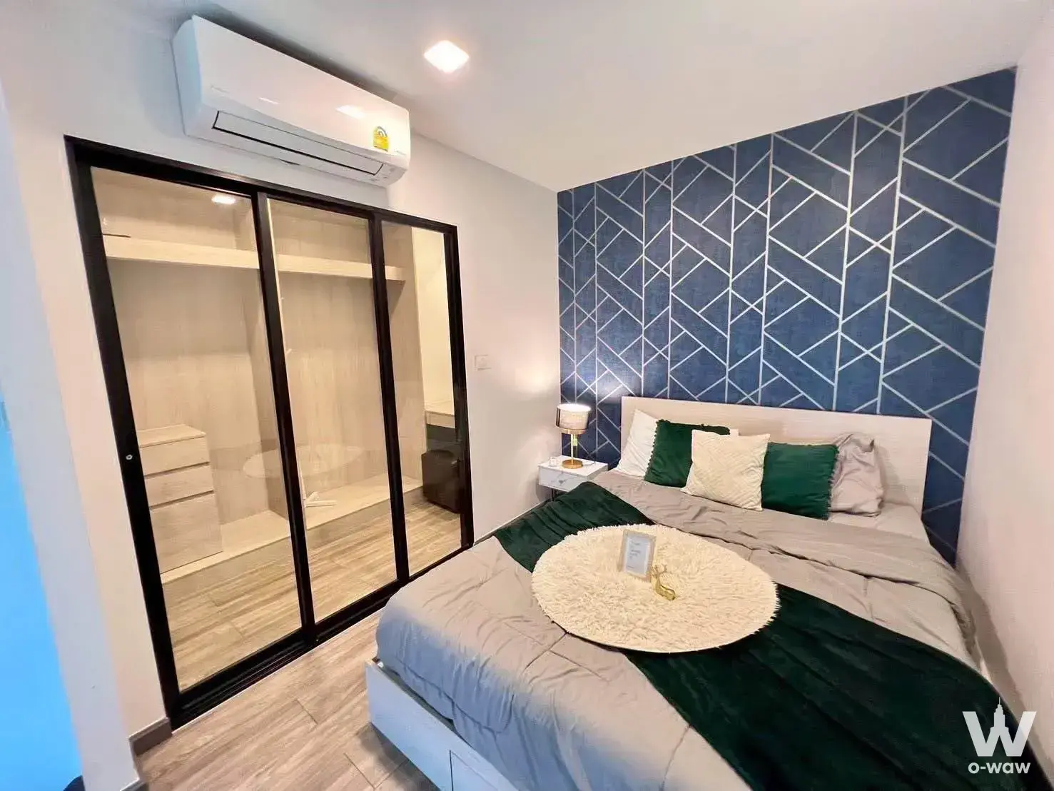 Bedroom with navy feature wall and glass wardrobe in a 1-bed The Collect Ratchada 32 condo for rent