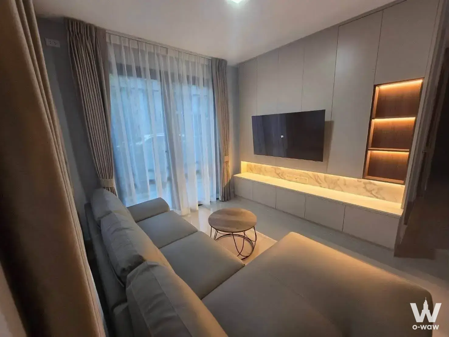 Living room in a 3-bed townhouse at Grande Pleno Sukhumvit-Bangna with L-shaped sofa and floor-to-ceiling windows