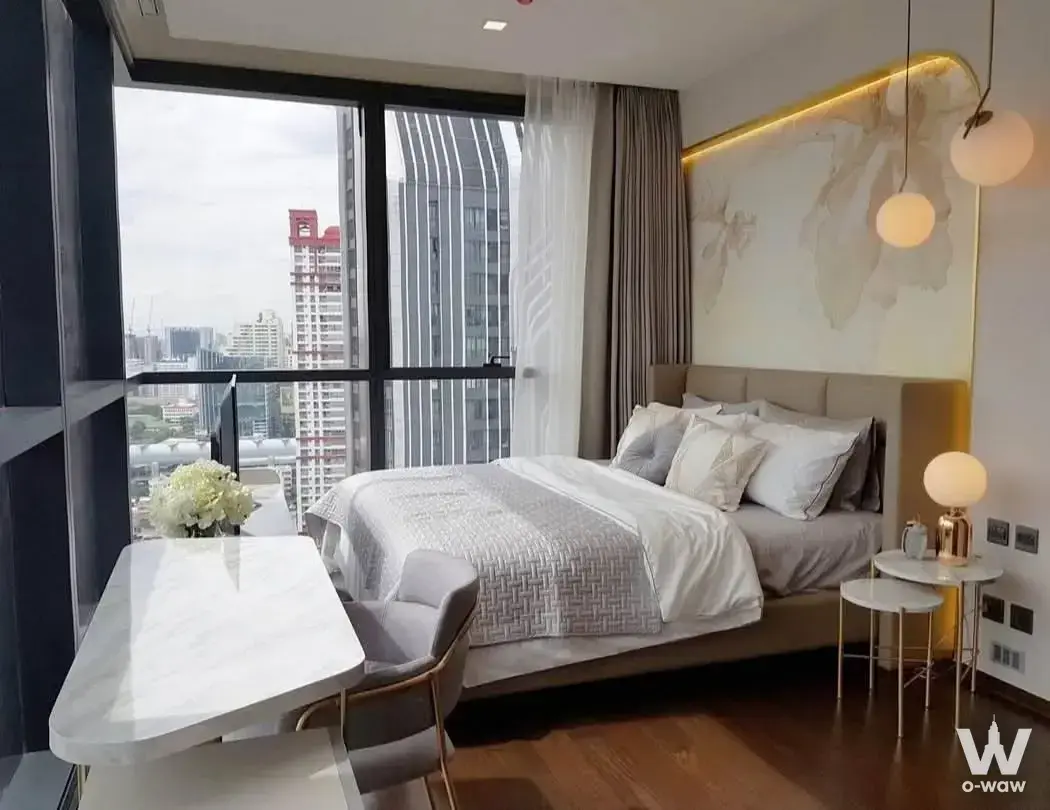 Luxury master suite in a THE LINE Ratchathewi condo featuring floral wallpaper, gold pendants, and a city skyline view