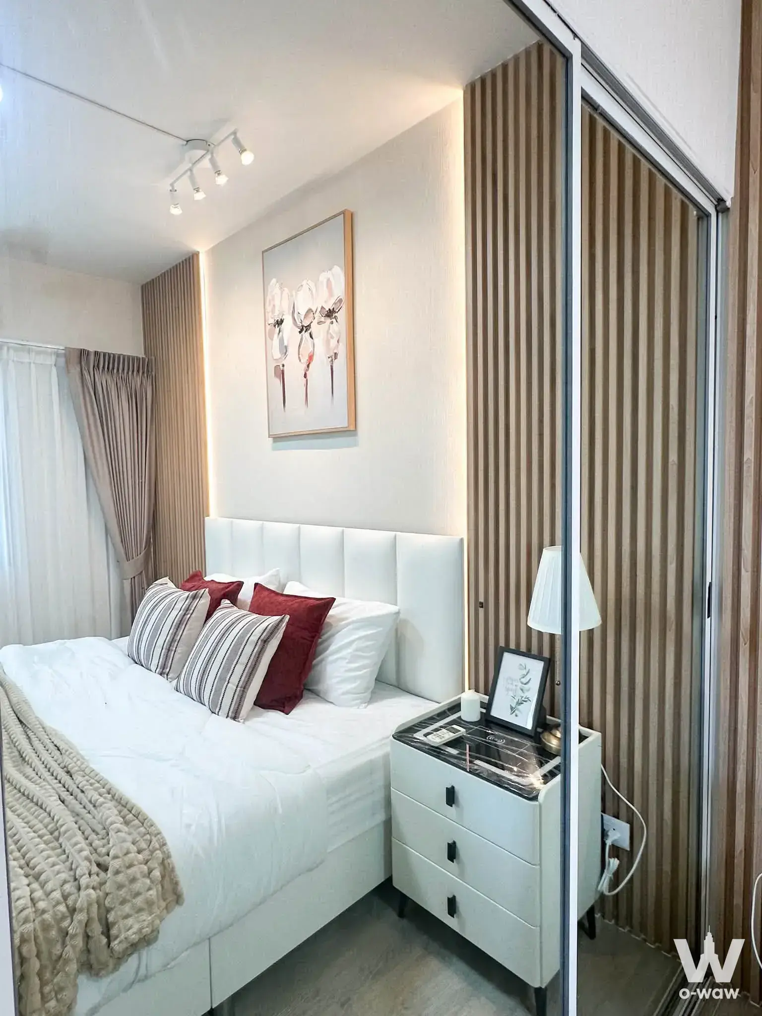 Modern bedroom in 1-bed A Space condo for sale featuring wood-slat walls, queen bed, and natural light