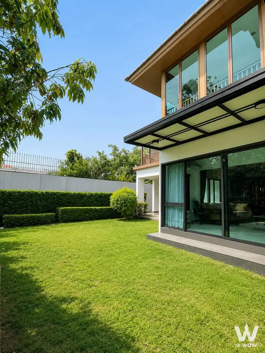 Modern 4-bed villa for sale in Burasiri Pattanakarn with wood cladding, glass windows, and a manicured green lawn