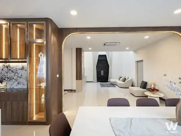 Modern living dining area in 4-bed house for sale at The City Ramintra-Wongwaen 2 with dark wood cabinetry and white sofa