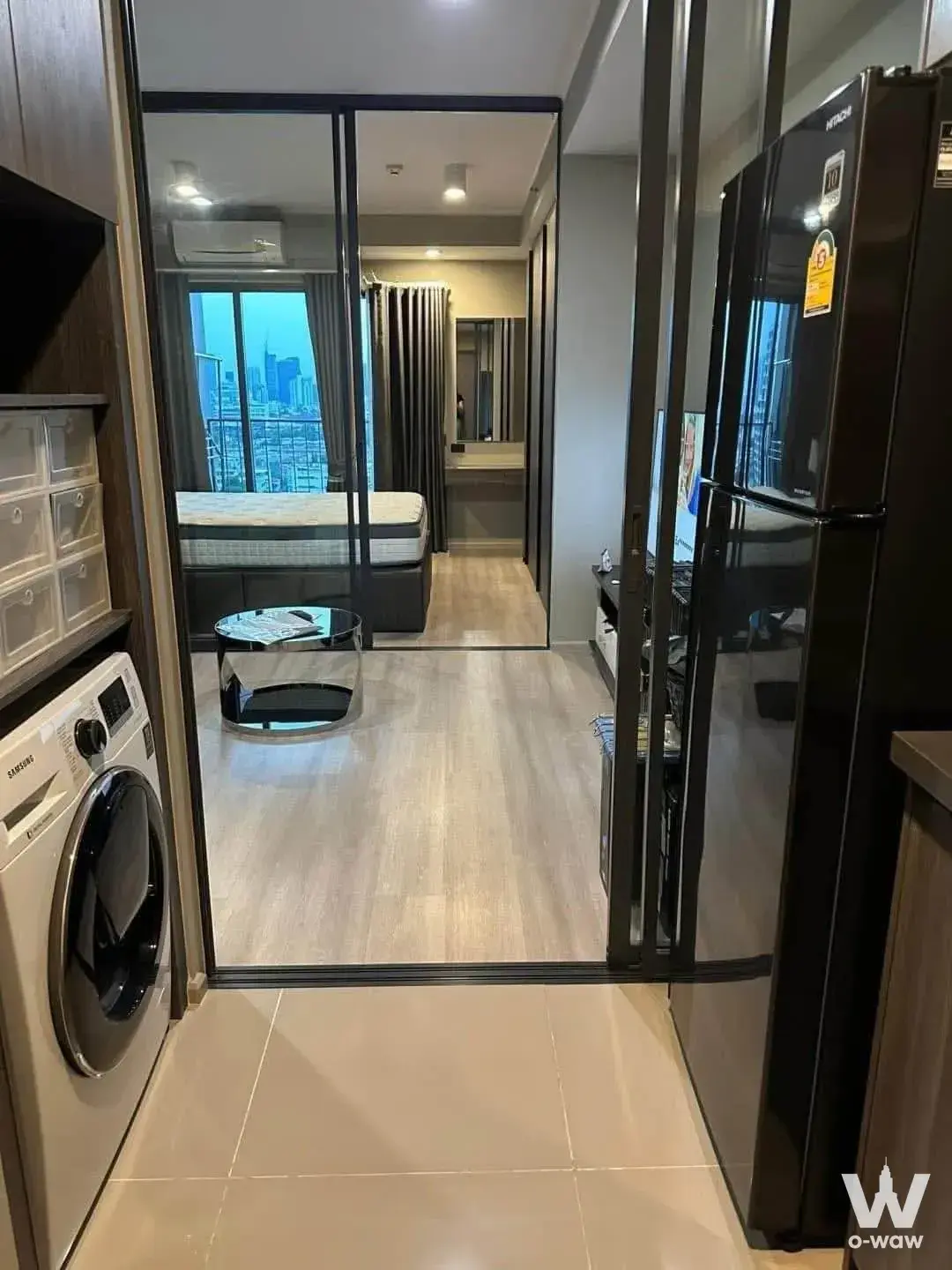 Modern 1-bed condo for rent in Ideo Ratchada-Sutthisan with queen bed, kitchenette, and city skyline view at dusk