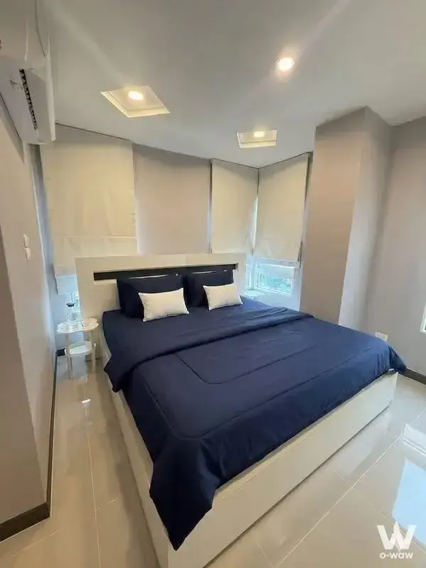 Modern bedroom in 1-bed condo for rent at Happy Condo Rachada 18 with navy linens and city view