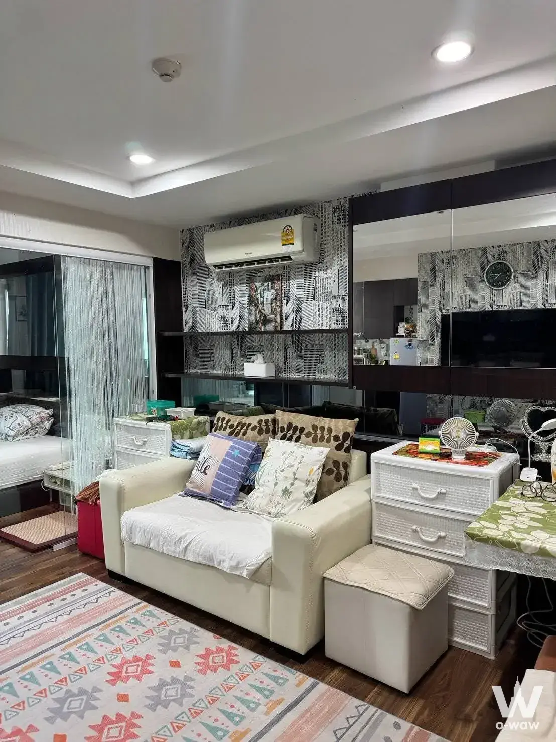 1-bed condo for sale in Parc Exo Kaset-Nawamin featuring cream leather sofa, black cityscape wallpaper, and eclectic decor