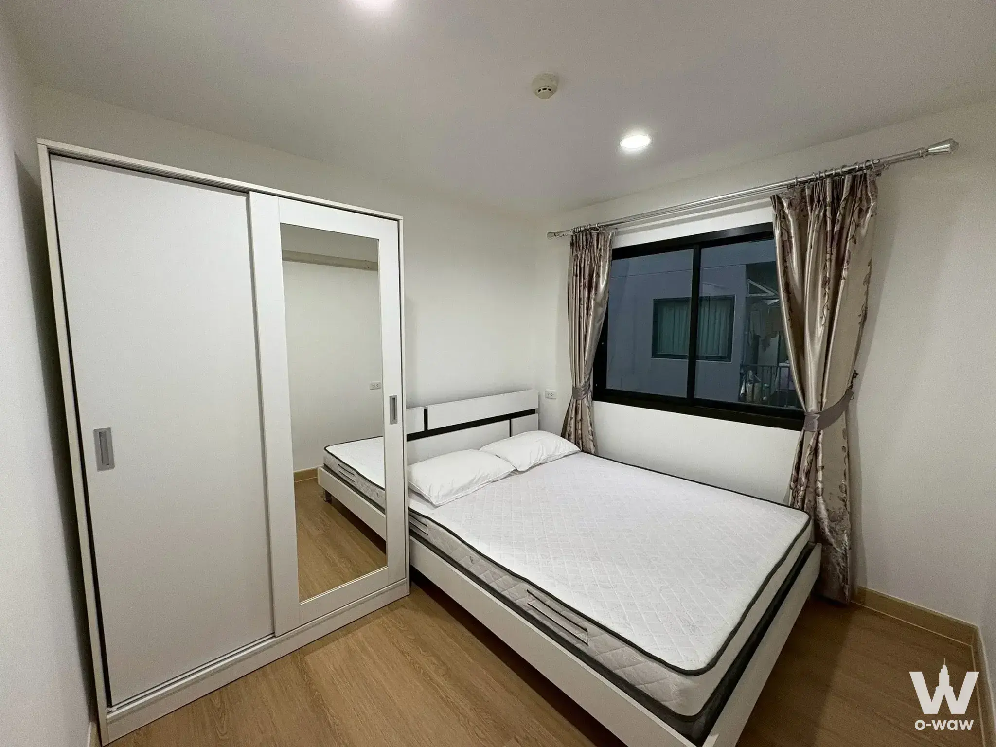 Bedroom in a 1-bed B-loft Sukhumvit 115 condo for sale features a white storage bed and mirrored sliding wardrobe