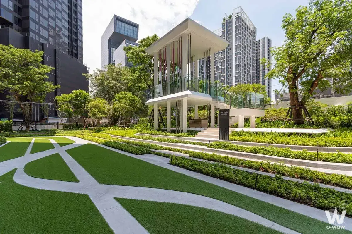 Landscaped garden at Life Asoke - Rama 9 featuring a white pavilion, green lawns, and high-rise towers