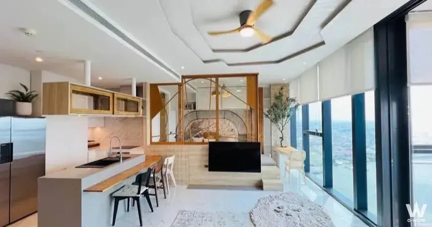 Open-plan kitchen and living room in a Canapaya Residences 2-bed condo with island bar and city-view windows