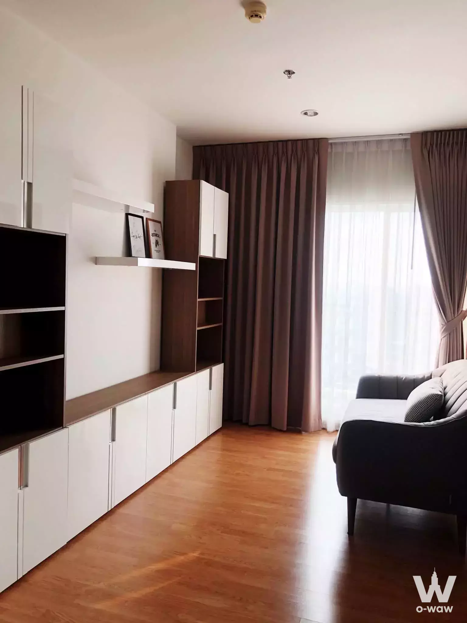 Modern living room in 1-bed condo for rent at The Parkland Ratchada featuring wood floors, built-in storage, and large