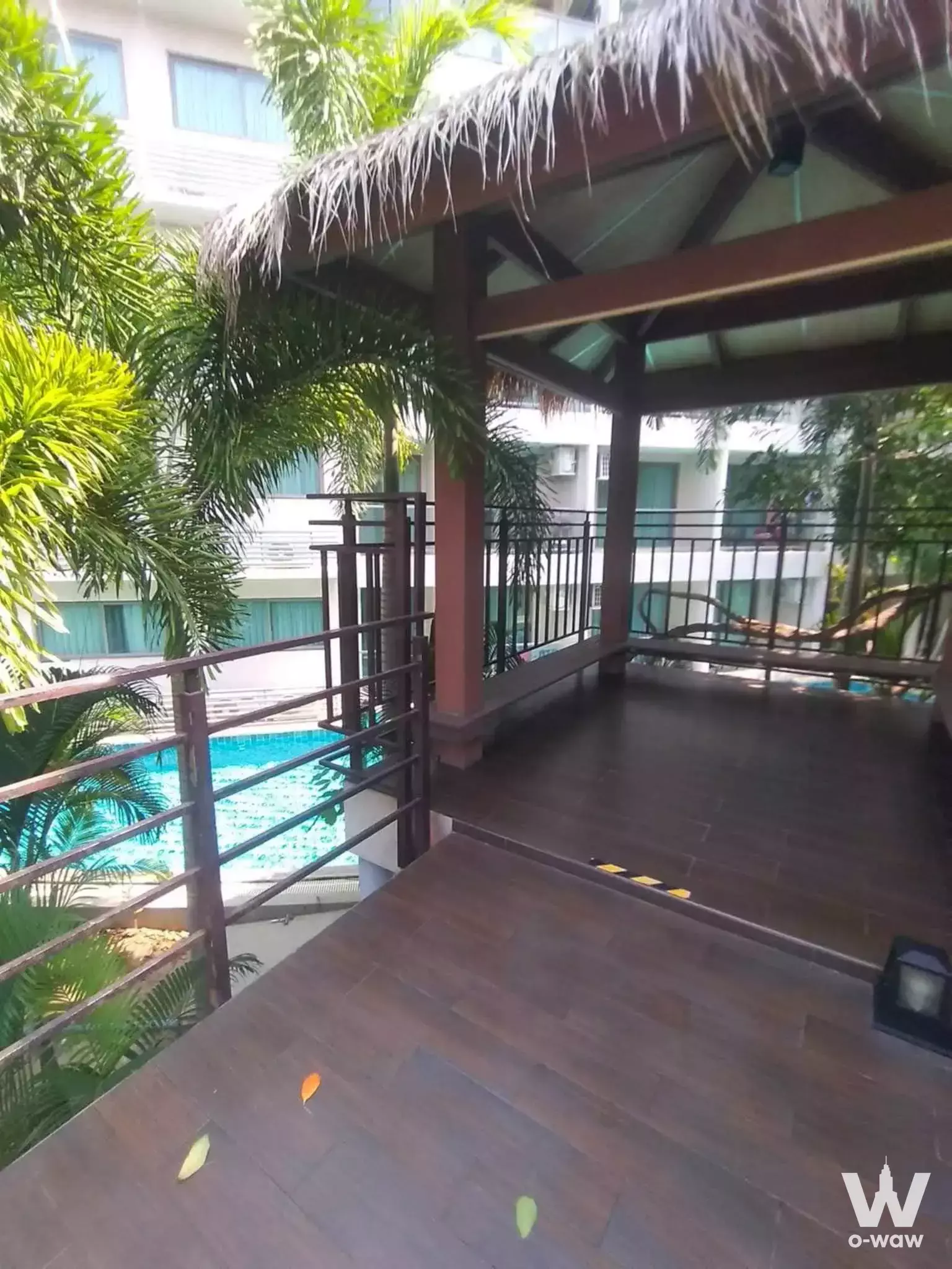 Covered balcony with thatched roof overlooking blue pool at Laguna Beach Resort 3 Maldives 1-bed condo for rent