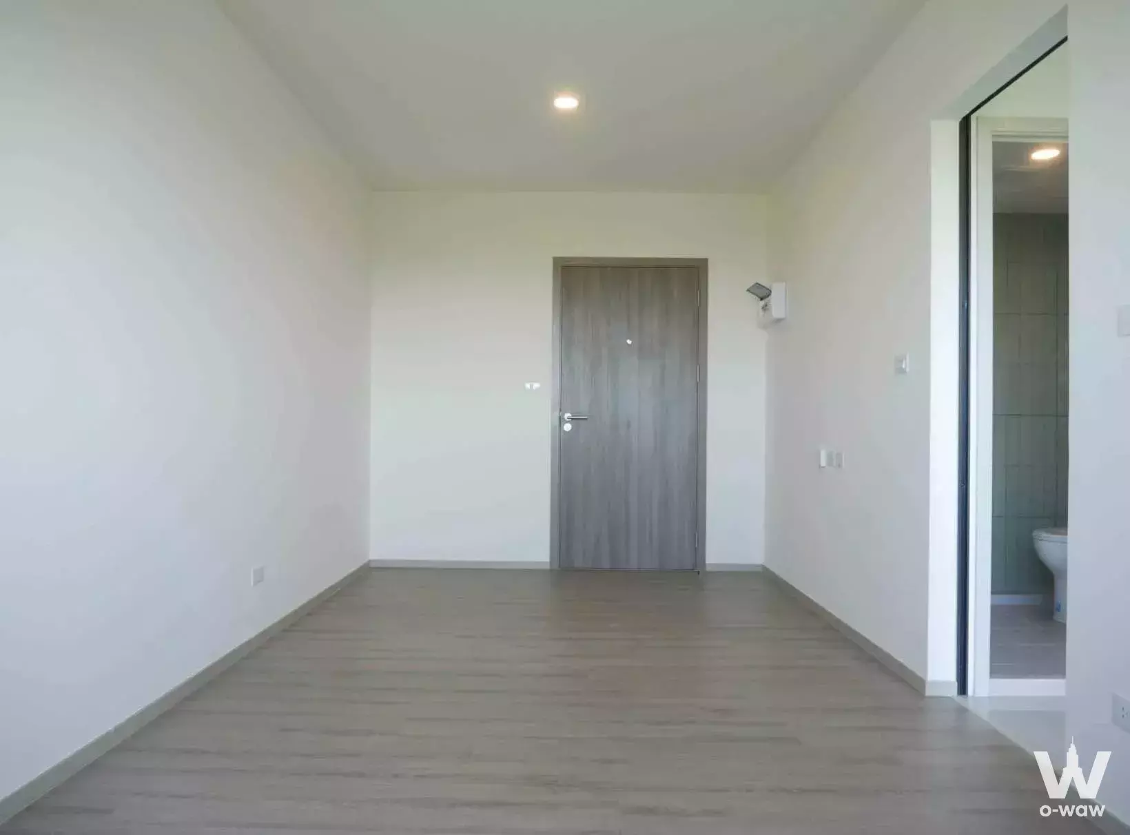 Empty bedroom in 1-bed condo for sale at The Origin Bangkae with grey laminate floors and white walls