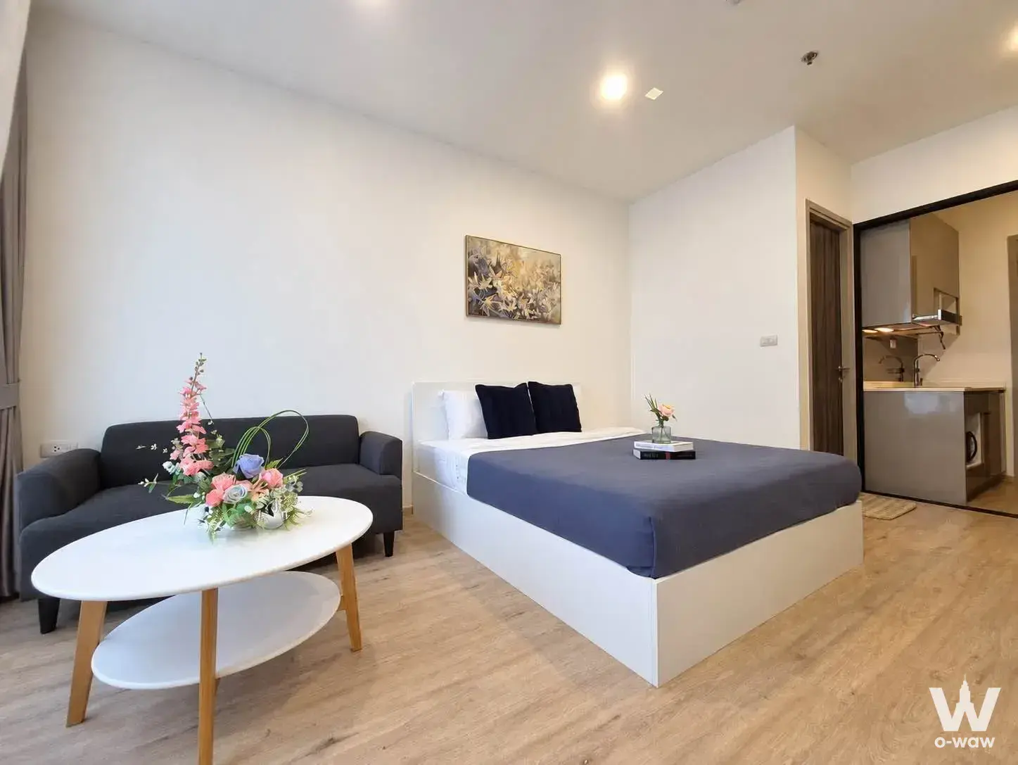This bedroom in a 1-bed rental condo at The Rich Rama 9 - Srinakarin has a queen bed and an open kitchen