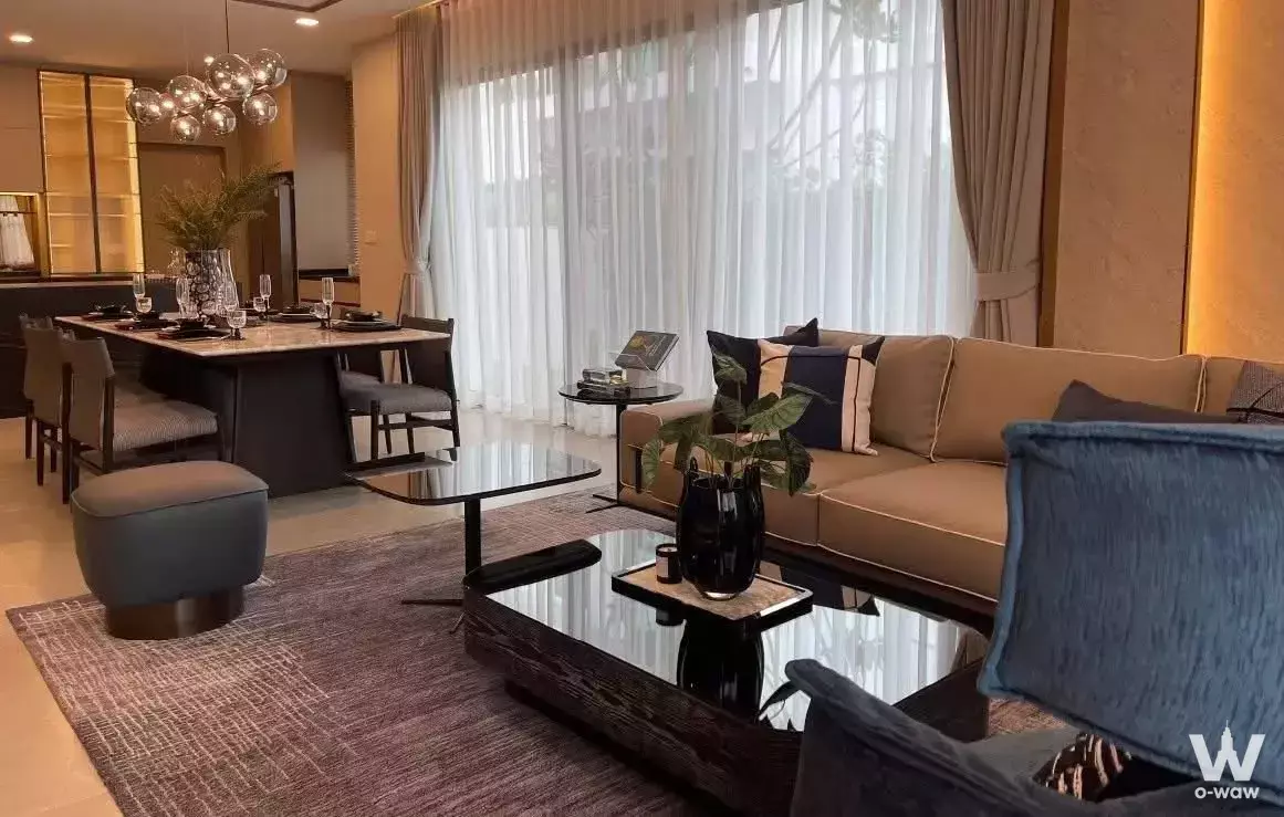 Modern open-plan living and dining area with L-shaped sofa, blue velvet armchair, and stone-top table in 4-bed house for
