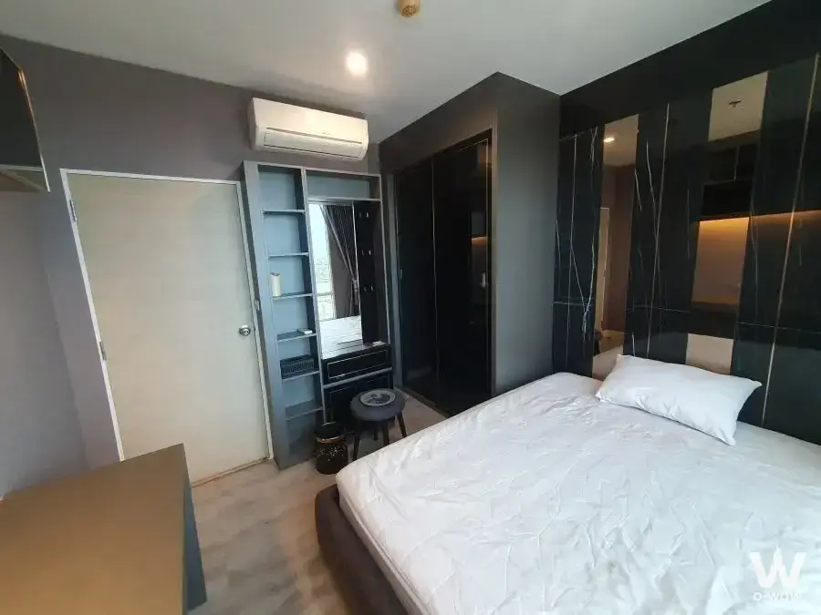 Queen bed in modern 1-bed condo for rent at The Sky Sukhumvit with black marble accent wall and grey built-in wardrobe