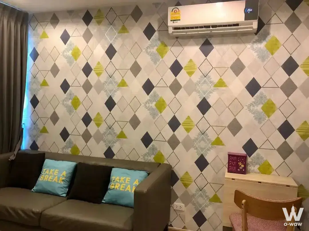 Bright living room in 1-bed Ideo Wutthakat condo with geometric wallpaper and leather sofa